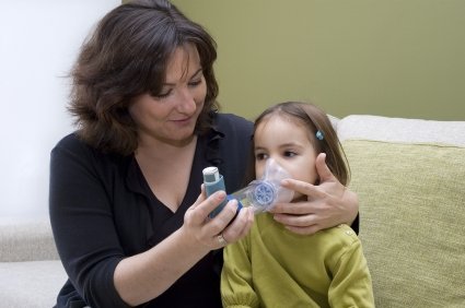 Woman helping girl take reliever inhaler with spacer