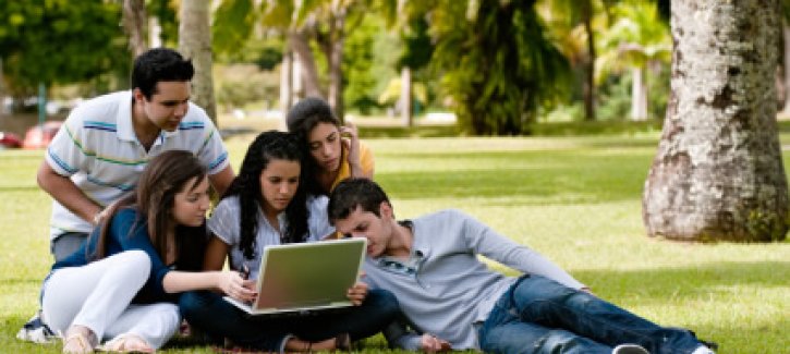 Group of student gathered round a laptop outside