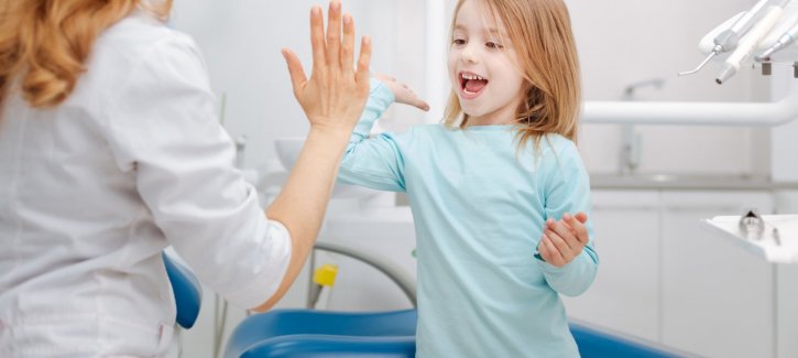 Blonde doctorn high-fiving small child